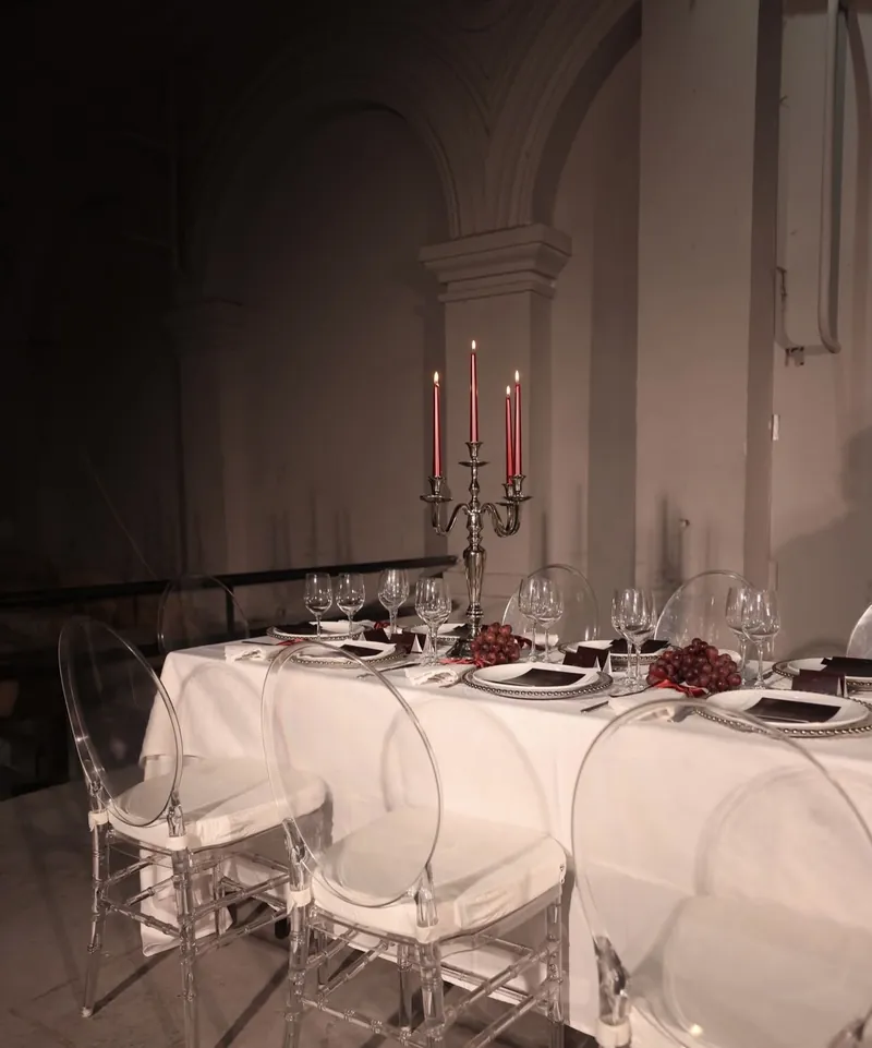 Detalle de la mesa con sillas transparentes, copas y candelabro con velas rojas